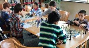 Young people sitting at tables playing chess. 